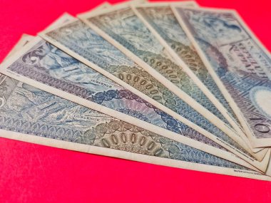 1963 'te yayınlanan eski Endonezya banknotlarının yüksek açılı görüntüsü. Kırmızı arkaplanda izole edilmiş rupiah para birimi kavramı.