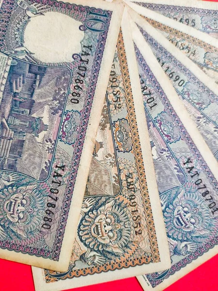 インドネシアの古い銀行券のトップビューRp 10ルピアは1963年に発行されました 赤い背景に隔離された古いルピア通貨の概念 — ストック写真