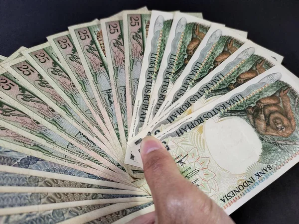 Eski Endonezya banknotlarını tutan adam. Siyah arka planda izole edilmiş eski rupiah para birimi kavramı. Yan açı görünümü