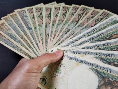 Eski Endonezya banknotlarını tutan adam. Siyah arka planda izole edilmiş eski rupiah para birimi kavramı. Yüksek açı görünümü