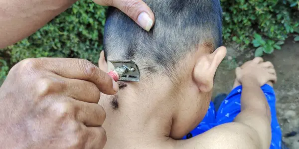 This boy had his hair cut by a barber. Barbers themselves usually shave manually using scissors and combs or using hair cutting tools at a barbershop.