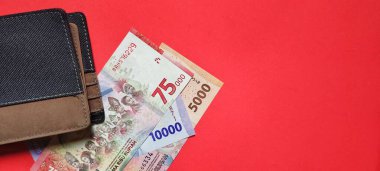 Bir cüzdan ve yeni rupiah banknotları 2022 'de kırmızı arka planda izole edilmiş.