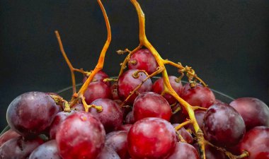 Siyah arka planda izole edilmiş bir kasedeki kırmızı üzümlerin yakın görüntüsü.