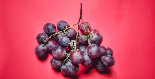 Vitis vinifera ya da kırmızı üzümler yüksek açılı bir açıdan fotoğraflanmış ve kırmızı arkaplanda izole edilmiş..