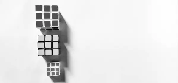 CENTRAL JAVA, INDONESIA - 25 Nisan 2024: Arkaplan olarak soyut fotoğraf kavramına sahip siyah ve beyaz fotoğraf. Objeye gölge etkisi vererek üç Rubik 'in fotoğrafının üst görünümü.