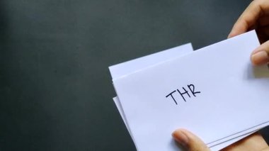 Bir adam THR ya da Tunjangan Hari Raya etiketli beyaz zarfları sayar. Bu maaş ikramiyesi Müslüman çalışanlara verilir.