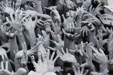 Çim biçen eller yerden yükselir. Umutsuzluk, acı, arzu. Evcilleştirilmemiş arzuları simgeleyen eller. Bu eller Tayland, Chiang Rai 'deki Wat Rong Khun (Beyaz Tapınak)' da bulunabilir.