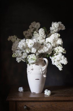 Beyaz vazoda beyaz leylaklar, ahşap masada.