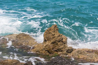 Dalgalar Yunanistan 'da kayalık plajları vuruyor. Dalgalı denizle yaz günü.