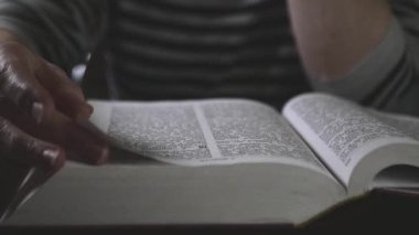 Hands gliding on the sheets of the red book I open and read the Bible 4k Cinematic Slow motion