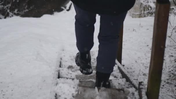 一个身穿黑衣的女孩走下铺着雪的楼梯 — 图库视频影像