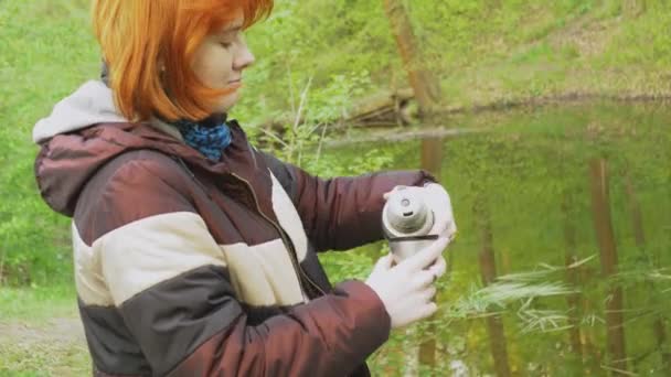 Ένα Κοκκινομάλλικο Κορίτσι Στο Δάσος Ρίχνει Τσάι Από Ένα Γκρι — Αρχείο Βίντεο