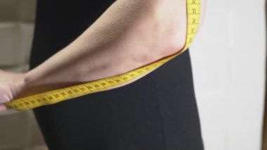 Bir kadın kolunun uzunluğunu 4K video düzenleme için bir santimetre bant ile ölçer.