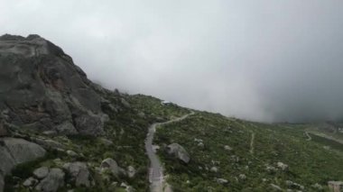 Dolambaçlı yolların, kayalık manzaraların ve dingin bir gölün bulunduğu sisli dağlık arazide bir yolculuk..