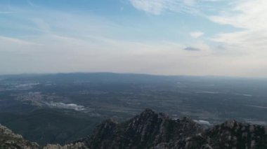 Kesinlikle nefes kesici bir panoramik manzara görkemli dağlar ve sakin bir gökyüzünün altında uzak bir şehir manzarası sergiliyor.