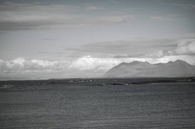 Dağları ve bulutları olan siyah ve beyaz İzlanda deniz manzarası