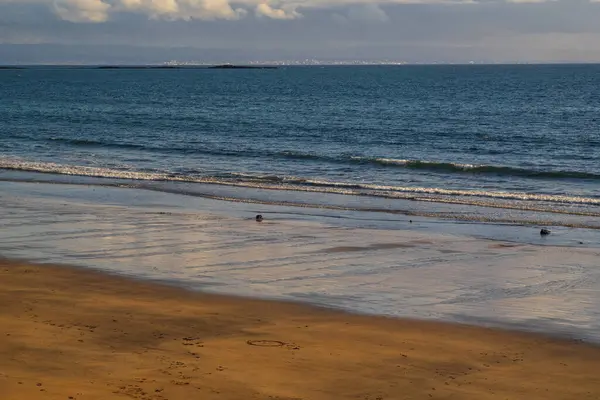 Sakin okyanus dalgaları ve bulutlu ufuklarıyla kumsal