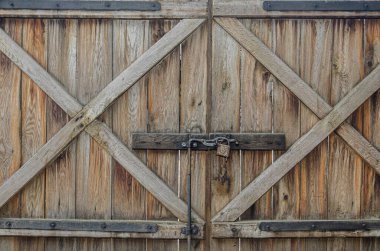Eski desenli kahverengi tahtaların ahşap yüzeyi paslı bir kilide yakın. Metal kilidi olan eski ahşap kapı. Kahverengi ahşap kapılı, kilitli.