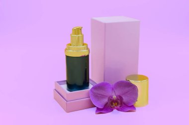Açık kutuda yüz serumu ve pembe kağıtta orkide çiçeği.