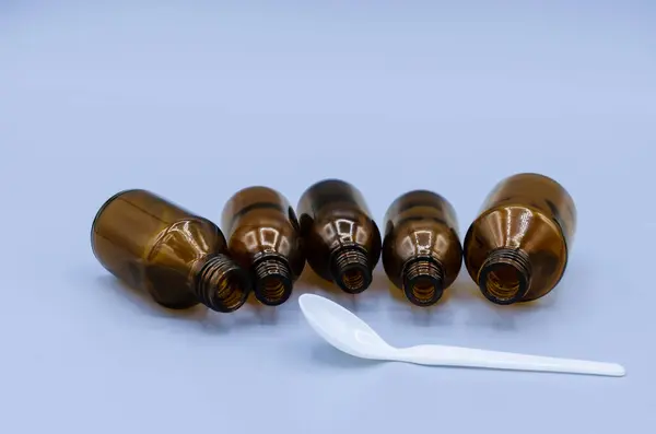Empty medical bottles of brown color and a measuring spoon on a blue background
