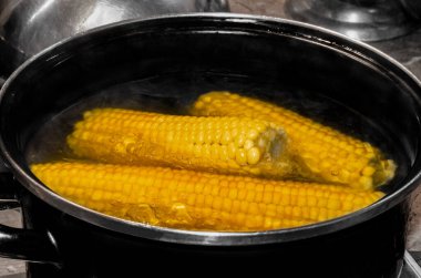 Sarı olgun mısır, metal bir tavada kaynar suda kaynatılır.