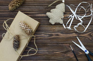 Yılbaşı hediyelerinin paketlenmesi bir köknar ağacının yaratıcı dekoru. Makas, ahşap bir masanın üzerindeki kablo. Noel ağacını kendi ellerinle süslemek için el sanatları. Yukarıdan görüntüle