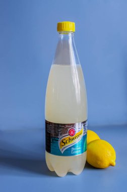 Odessa, Ukrayna, 8 Mart 2024: Mavi arka planda cam bir şişe Schweppes ve iki limon