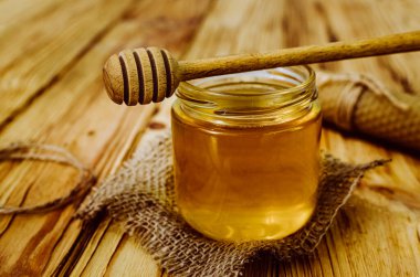 Tahta bir masa ve çuval bezi üzerinde bal kavanozu.