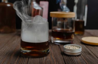 Bardakta tütsülenmiş viski kokteyli, içkiden yükselen dumanlı.. 