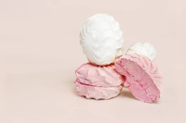 Hassas pembe ve beyaz zefirin yakın plan kompozisyonu. Pembe bir zefir, havadar dokusunu sergilerken beyaz bir zefir ise tepesinde duruyor. Görüntü yumuşak pembe bir arkaplana göre ayarlandı.