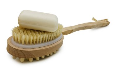 Üzerinde hafif tüyleri olan doğal bir ahşap banyo fırçası ve beyaz arka planda izole edilmiş bir sabun kalıbı. Bu görüntü, doğal hijyen, sağlık ve özgüven duygularını çağrıştırıyor..