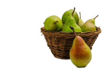 Olgun bir armudun canlı, yakın çekim görüntüsü, kırmızı bir ipucu, kırsal bir hasır sepete yaslanmış, başka taze yeşil armutlarla dolup taşıyor..