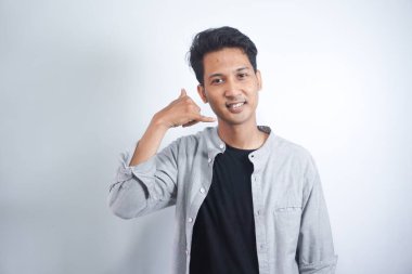 Genç yakışıklı Asyalı adam izole edilmiş bir şekilde telefon jesti yapıyor. Bana geri dönüş işareti ver.