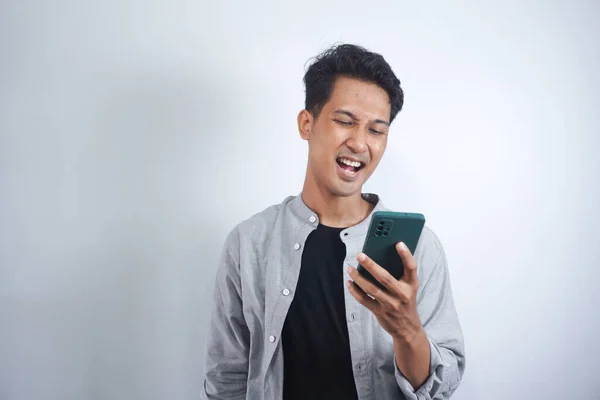 穿着一件基本衬衫 用智能手机 浏览互联网 社交媒体的积极的亚洲人 站在孤立的白色背景上 看着相机 面带微笑 — 图库照片