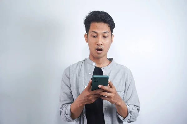 Junger Asiatischer Mann Mit Überraschtem Gesichtsausdruck Hält Smartphone Der Hand — Stockfoto