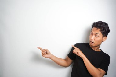 Tecrit edilmiş genç yakışıklı bir adam bir ürün sunmak için kenarı işaret ediyor.