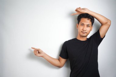 Tecrit edilmiş genç yakışıklı bir adam bir ürün sunmak için kenarı işaret ediyor.