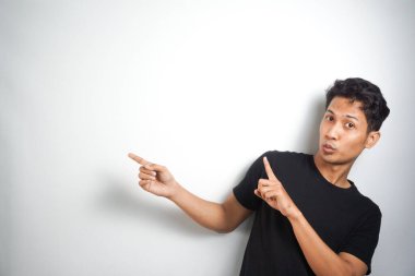 Tecrit edilmiş genç yakışıklı bir adam bir ürün sunmak için kenarı işaret ediyor.