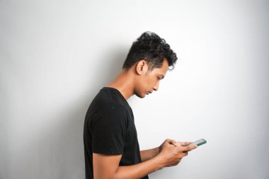 Asian man seriously concentrated on smartphone isolated on white background.