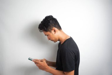 Asian man seriously concentrated on smartphone isolated on white background.