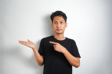 Tecrit edilmiş genç yakışıklı bir adam bir ürün sunmak için kenarı işaret ediyor.