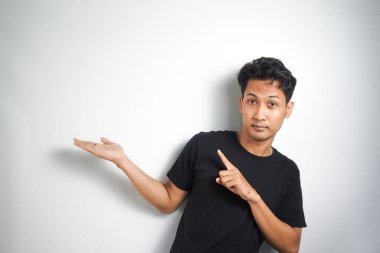 Tecrit edilmiş genç yakışıklı bir adam bir ürün sunmak için kenarı işaret ediyor.