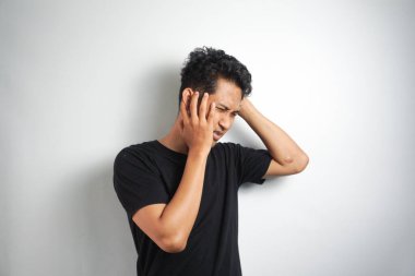 Beyaz arka planda elleri başının üstünde duran bir adam portresi..