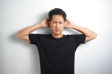 Beyaz arka planda elleri başının üstünde duran bir adam portresi..