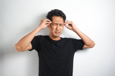 Beyaz arka planda elleri başının üstünde duran bir adam portresi..