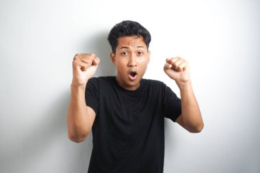 Asyalı heyecanlı bir adam beyaz arka planda iki yumrukla başarıyı kutluyor. Yakın çekim, stüdyo çekimi, mutluluk, olumlu duygu ve his. Yaptım bile. yüz ifadesi