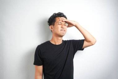 Beyaz arka planda elleri başının üstünde duran bir adam portresi..