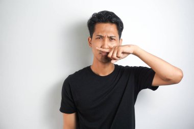 tiksinti adam portre parmakları ile burun çimdikler tiksinti bir şey koku durum gri duvar arka plan izole kokuyor görünüyor. İnsan yüz ifadesi vücut dili tepki