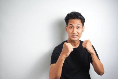 Hadi dövüşelim. Heyecanlı, kendinden emin erkek modelin portresi, yumruklarını kaldırması, boksör pozu vermesi, barda sarhoş olup da beyaz duvarın üzerinden birini yumruklamak istemesi.