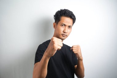 Hadi dövüşelim. Heyecanlı, kendinden emin erkek modelin portresi, yumruklarını kaldırması, boksör pozu vermesi, barda sarhoş olup da beyaz duvarın üzerinden birini yumruklamak istemesi.